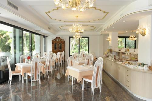 a dining room with white tables and white chairs at Parc Hotel Flora S in Riva del Garda
