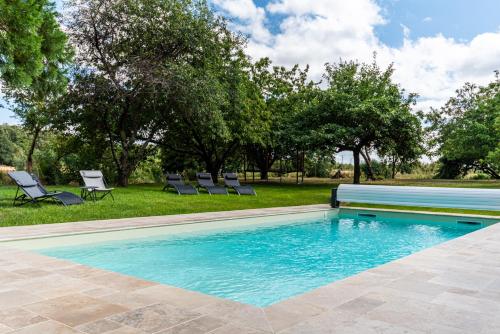 - une piscine dans une cour avec des chaises et des arbres dans l'établissement Manoir de Rousse 320 m2 en campagne Piscine Wifi Jardins, à Denezé-sous-Doué