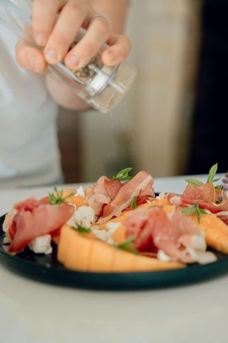 a person holding a glass of water next to a plate of food at Maison Groleau in Mombrier