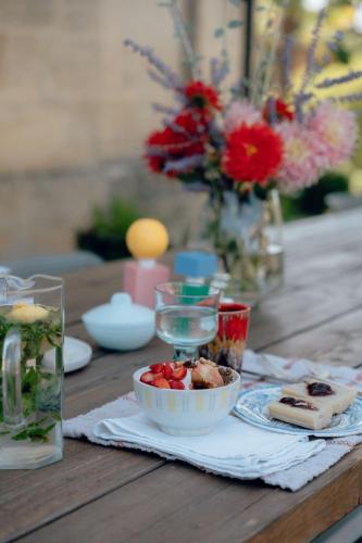 a wooden table with a bowl of food and flowers at Maison Groleau in Mombrier