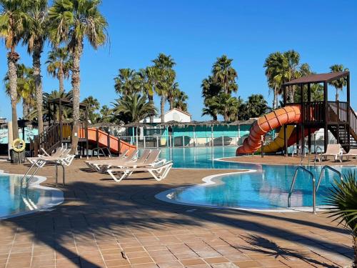 a resort pool with a slide and a playground at Appartement près de la plage in Corralejo