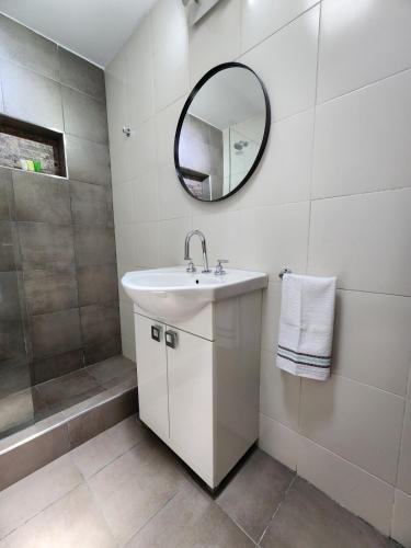 a white bathroom with a sink and a mirror at Casa Francisco in Paraná