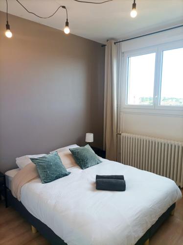 une chambre avec un grand lit blanc avec une fenêtre dans l'établissement Bel appartement tout équipé, au Mans