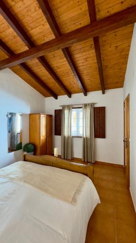 a bedroom with a large white bed with wooden ceilings at Vela de Estai in Vila Nova de Milfontes