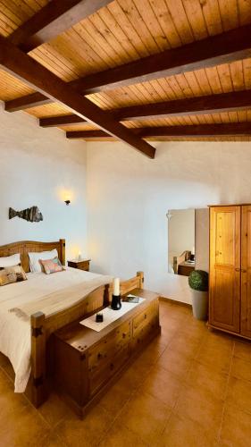 a bedroom with a large bed and a wooden ceiling at Vela de Estai in Vila Nova de Milfontes