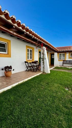 a house with a deck with a table in the yard at Vela de Estai in Vila Nova de Milfontes