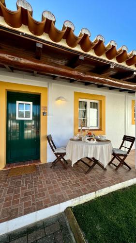 a patio with a table and chairs and a house at Vela de Estai in Vila Nova de Milfontes