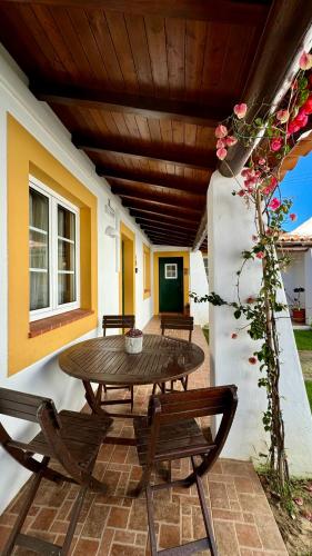 a wooden table and chairs on a patio with a table at Vela de Estai in Vila Nova de Milfontes
