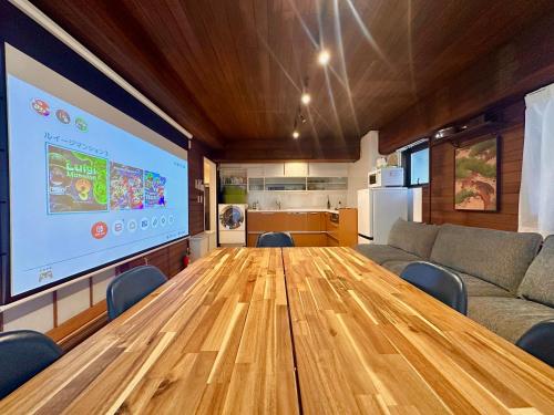 a conference room with a wooden table and a large screen at LoveAsakusaBigSpaceModernHome 浅草寺6分 浅草寺駅10分 2-8人 成田&羽田空港直通 in Tokyo