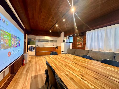 a conference room with a large wooden table and a large screen at LoveAsakusaBigSpaceModernHome 浅草寺6分 浅草寺駅10分 2-8人 成田&羽田空港直通 in Tokyo