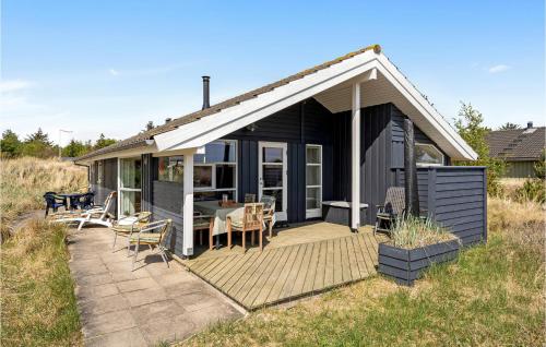 a black cottage with a table and chairs on a deck at Holiday Home Bunken 7 in Ålbæk