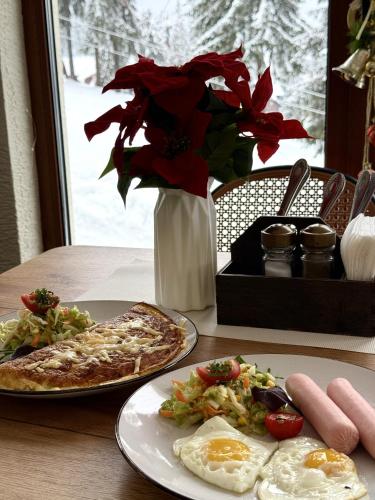 a table with two plates of pizza and a vase with flowers at Маріна Драгобрат in Dragobrat