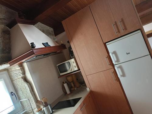 a small kitchen with a refrigerator and a microwave at Cabaña rústica playa Area, Viveiro, Lugo in Lago