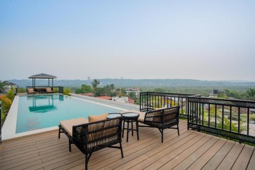 a balcony with a table and chairs and a swimming pool at ELIVAAS 1 BHK with Rooftop Pool - Kamerios Verano in Goa