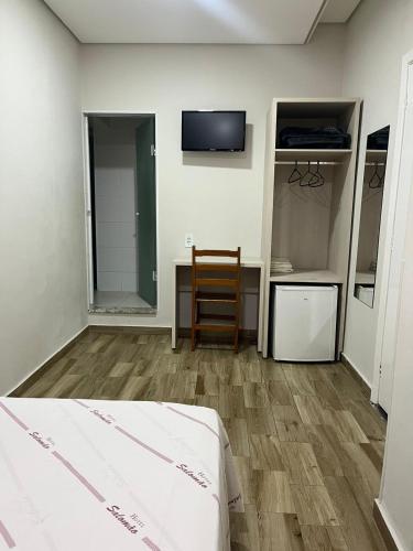 a room with a bed and a chair and a tv at Hotel Salomão - Próximo a 25 de Março, Bom Retiro, Brás e Rua Santa Efigênia, a 2 minutos do Mirante Sampa Sky e pista de Skate Anhangabaú in Sao Paulo