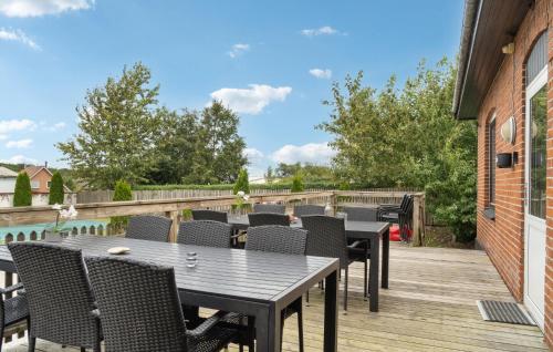 a patio with tables and chairs on a wooden deck at Nice Home In Ørum Djurs With Sauna in Nimtofte