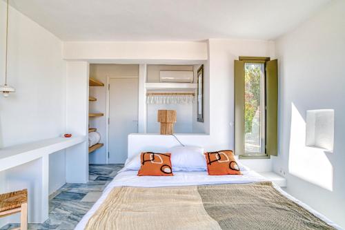 ein Schlafzimmer mit einem Bett und zwei orangefarbenen Kissen in der Unterkunft Stone Pine House Antiparos - Private Pool Villa in Andiparos