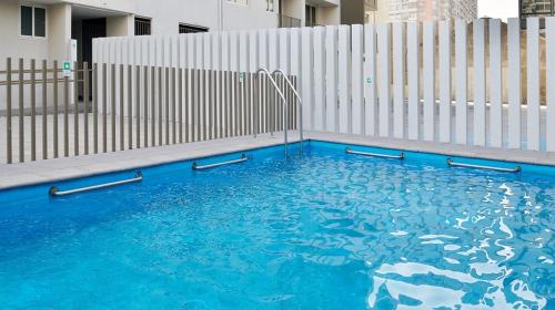 a swimming pool with blue water in front of a fence at Departamento Completo de Dos Habitaciones in Santiago
