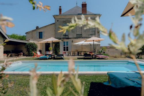 a house with a swimming pool in front of a building at Maison Groleau in Mombrier
