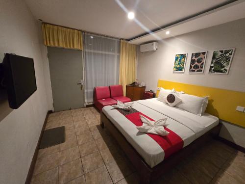 a bedroom with a large bed and a red chair at Kusma Hotel Bandungan Semarang in Semarang