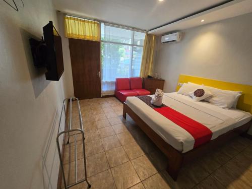 a bedroom with a bed and a red chair at Kusma Hotel Bandungan Semarang in Semarang