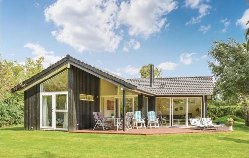 a house with glass doors and chairs on a lawn at Three-Bedroom Holiday Home In Dronningmolle in Dronningmølle