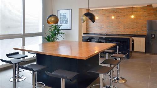 a kitchen with a wooden counter and bar stools at Departamento Completo de Dos Habitaciones in Santiago