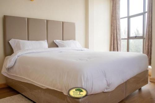 MweigaAberdare Juniper Green Gardens Resort的带窗户的房间里有一张白色的大床