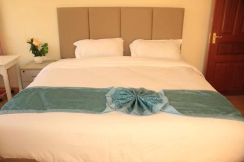 MweigaAberdare Juniper Green Gardens Resort的一张白色的床,上面有蓝色的弓形