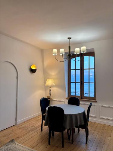 a dining room with a table and chairs and a window at Le Royal XIX Dinard vue mer luxe in Dinard