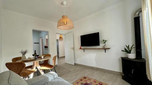 a living room with a table and a tv on a wall at Vela de Estai in Vila Nova de Milfontes