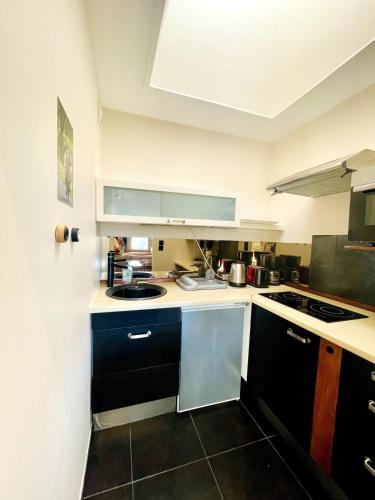 une cuisine avec des armoires noires et un comptoir blanc dans l'établissement Le Jeflys - Porte Royale, à La Rochelle