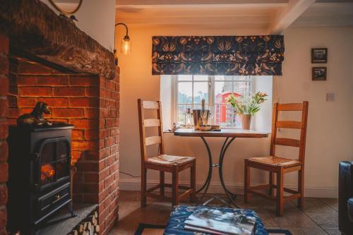 - un salon avec une cheminée en briques et une table dans l'établissement Nurse's Cottage, Tissington, Derbyshire, à Ashbourne