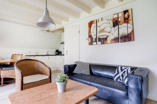 a living room with a black leather couch and a table at Winterkoning I Rustig Huisje met Tuin in Zwiggelte