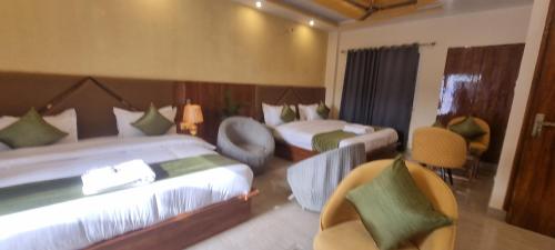 a hotel room with two beds and two chairs at Traveller's Paradise-Mountain View By Around Stays in Rishīkesh