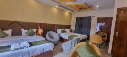 a hotel room with two beds and chairs at Traveller's Paradise-Mountain View By Around Stays in Rishīkesh