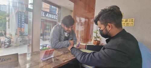 two men sitting at a table in a restaurant at Traveller's Paradise-Mountain View By Around Stays in Rishīkesh