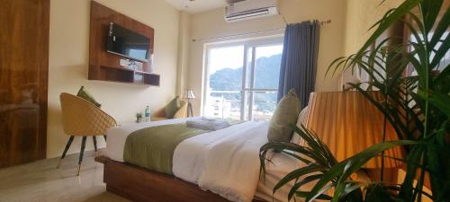a bedroom with a bed with a plant in front of a window at Traveller's Paradise-Mountain View By Around Stays in Rishīkesh