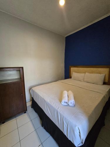 a bedroom with a bed with white slippers on it at Kusma Hotel Bandungan Semarang in Semarang