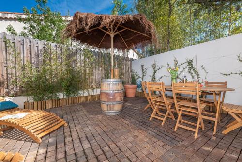 ジュアン・レ・パンにあるAppartement 6 pers Jardin Privé La Cabane Bambou - Mandara Beach , Antibes French Rivieraのテーブルと椅子と傘のあるパティオ
