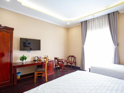 a hotel room with a desk and a table with chairs at Khách Sạn Sunrise Đà Lạt in Ấp Ða Lợi