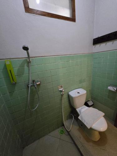 a green tiled bathroom with a toilet and a shower at Kusma Hotel Bandungan Semarang in Semarang