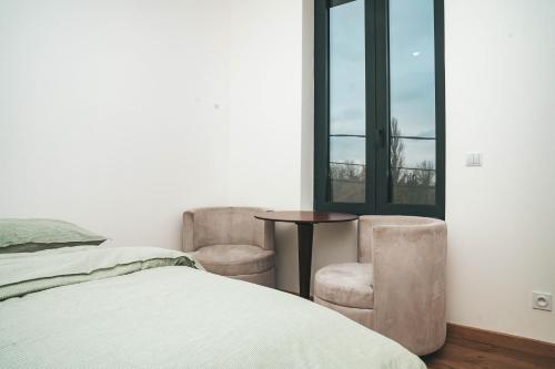 une chambre avec un lit et deux chaises et une fenêtre dans l'établissement Hostel Bords de Marne 2, à Gournay-sur-Marne