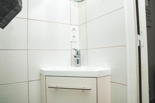 La salle de bains est pourvue d'un lavabo et de carrelage blancs. dans l'établissement Hostel Bords de Marne 2, à Gournay-sur-Marne