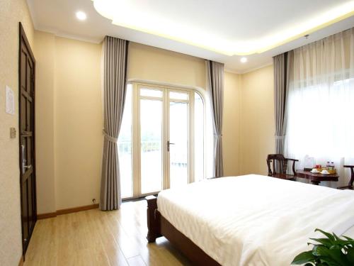 a bedroom with a bed and a large window at Khách Sạn Sunrise Đà Lạt in Ấp Ða Lợi