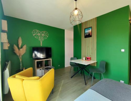 ein Wohnzimmer mit grünen Wänden, einem gelben Sofa und einem Tisch in der Unterkunft Hesperie studio in Chamalières