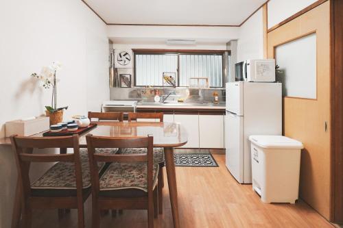 a kitchen with a table and a white refrigerator at 心斎橋まで7分 なんば1駅 Meeno Home 汐見 一軒家貸切 子ども歓迎 in Osaka