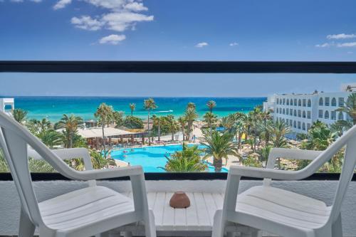 a balcony with two chairs and a view of the beach at Nozha Beach Resort & Spa in Hammamet