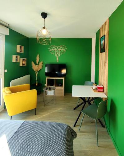 - un salon avec des murs verts, une table et des chaises dans l'établissement Hesperie studio, à Chamalières