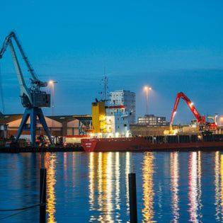 a harbor with cranes and a ship in the water at Villa Gertrud - Bed & Breakfast in Kolding